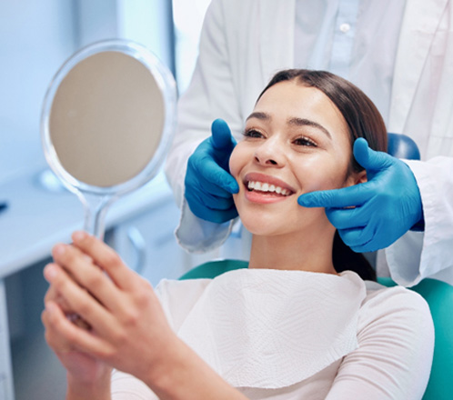 Patient smiling at reflection in handheld mirror