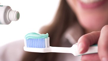 Lady applies toothpaste to brush